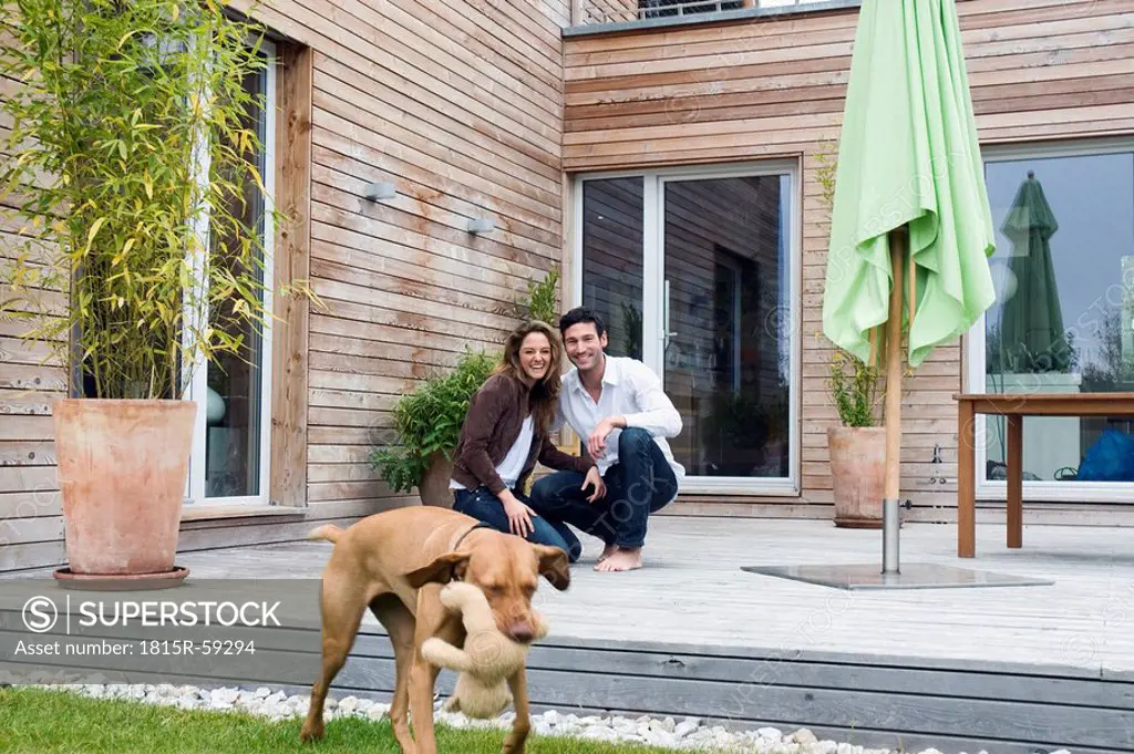 Germany, Bavaria, Munich, couple on terrace in front of house with dog