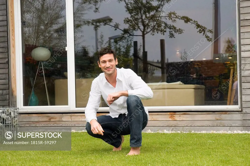 Young man squatting on lawn