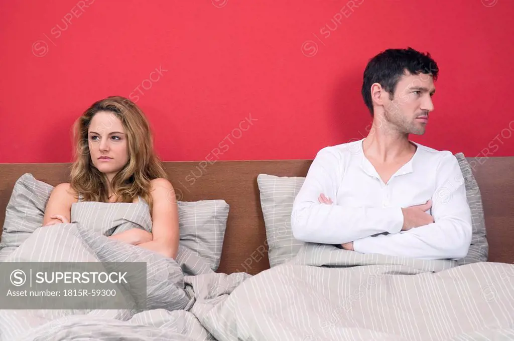 Young couple ignoring each other in bed, portrait