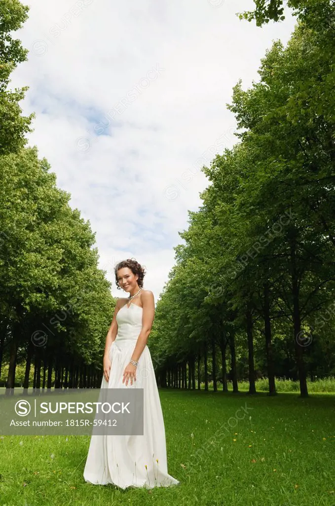 Germany, Bavaria, Bride standing in park, smiling, portrait