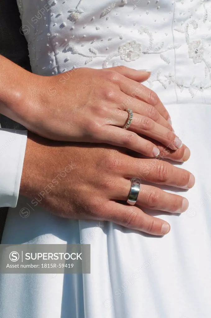 Germany, Bavaria, Bride and groom with wedding rings, mid section, close_up