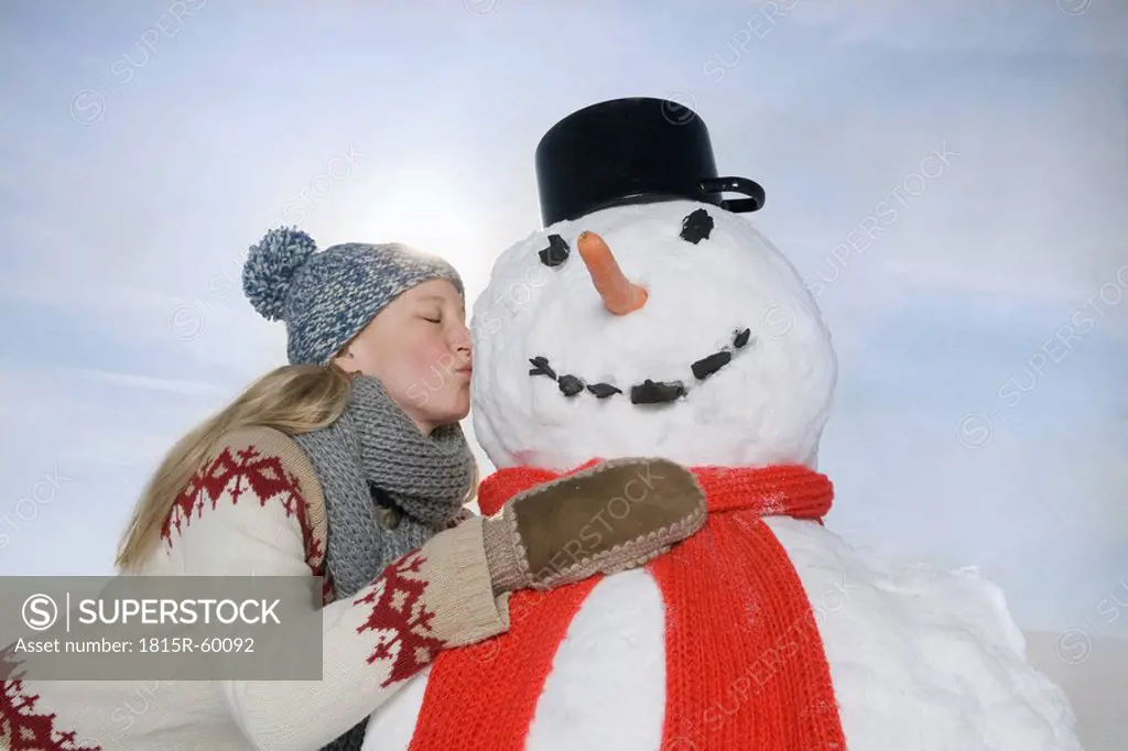 Germany, Bavaria, Munich, Young Woman Kissing Snowman, portrait