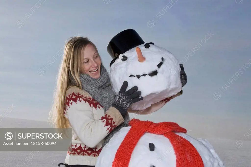 Germany, Bavaria, Munich, Woman making snowman, smiling, portrait