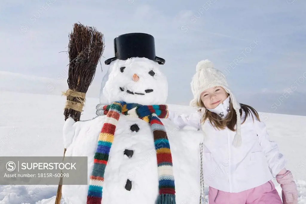 Germany, Bavaria, Munich, Girl 8_9 standing next to snowman, portrait