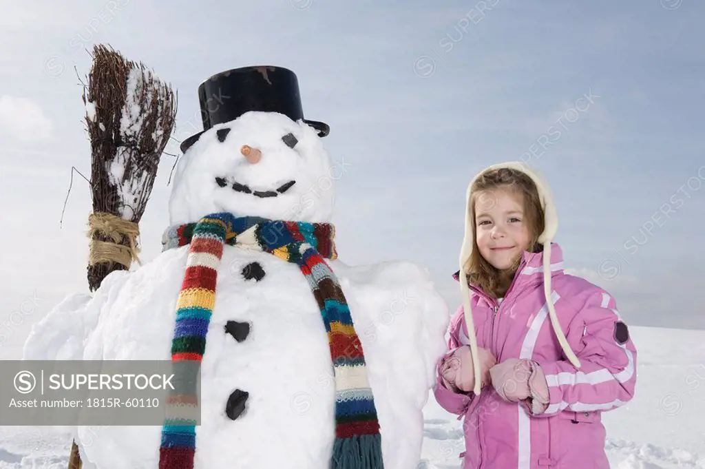 Germany, Bavaria, Munich, Girl 4_5 standing next to snowman, smiling, portrait