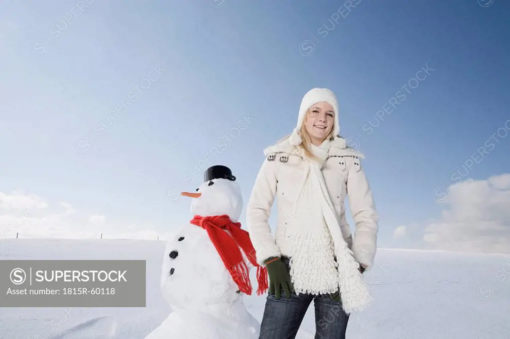 Germany, Bavaria, Munich, Woman standing next to snowman, portrait