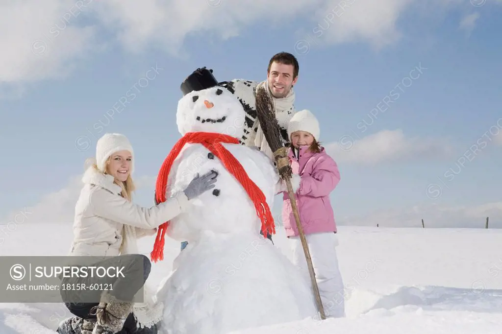 Germany, Bavaria, Munich, Family making a snowman, portrait