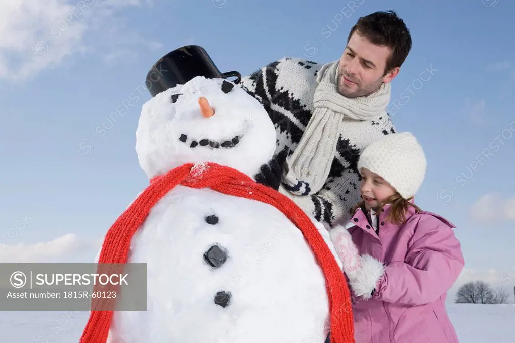 Germany, Bavaria, Munich, Father and daughter 6_7 making a snowman, portrait