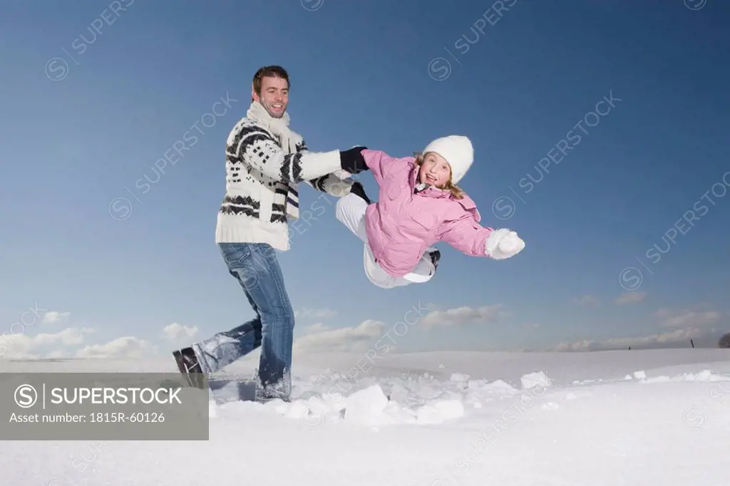 Germany, Bavaria, Munich, Father and daughter 6_7 in snowy landscape, having fun