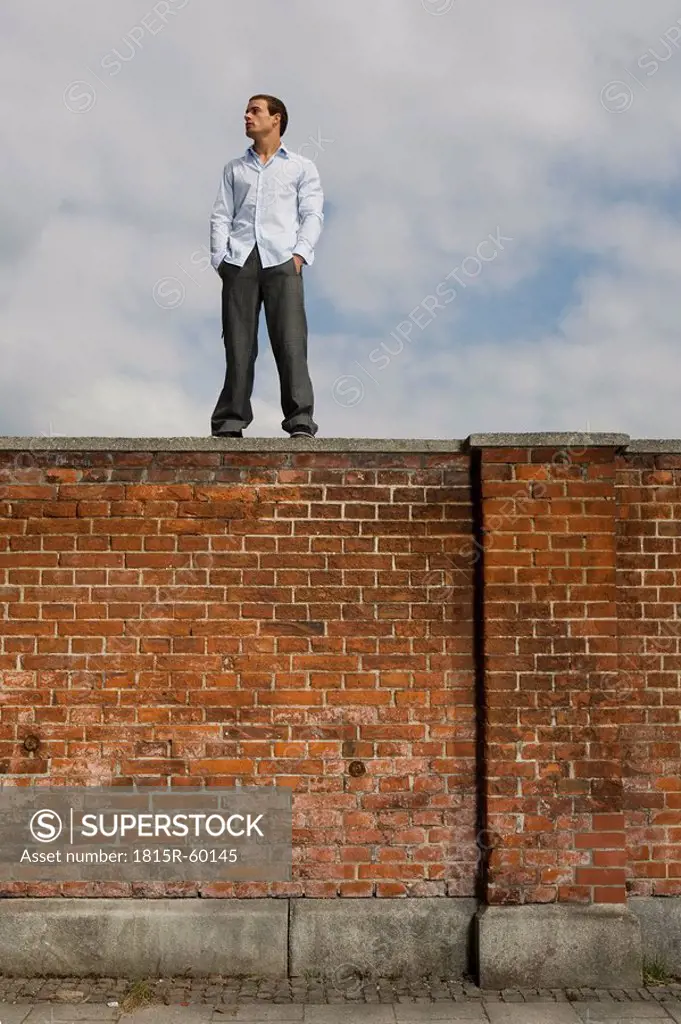 Germany, Bavaria, Munich, Young man standing on brick wall