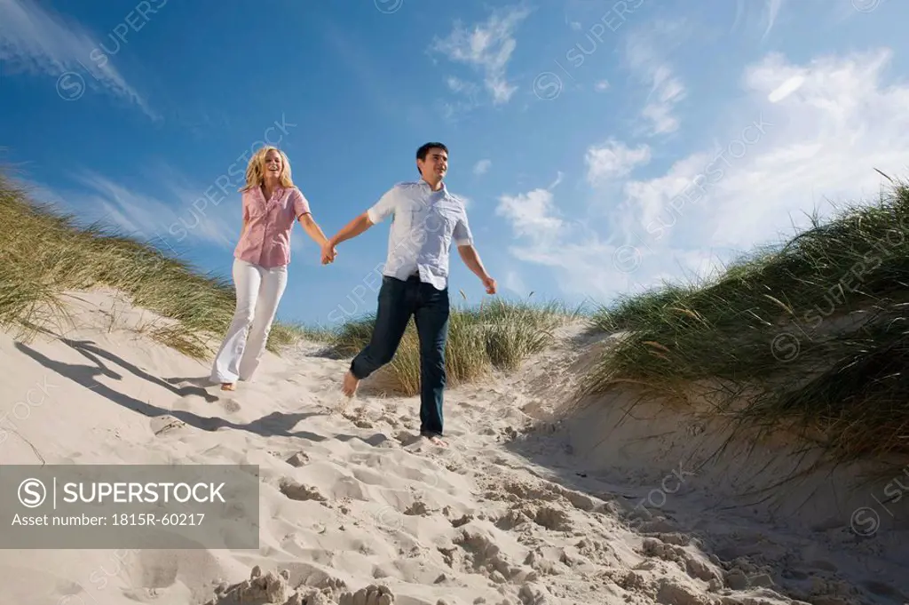 Germany, Schleswig Holstein, Amrum, Couple running in sand dunes