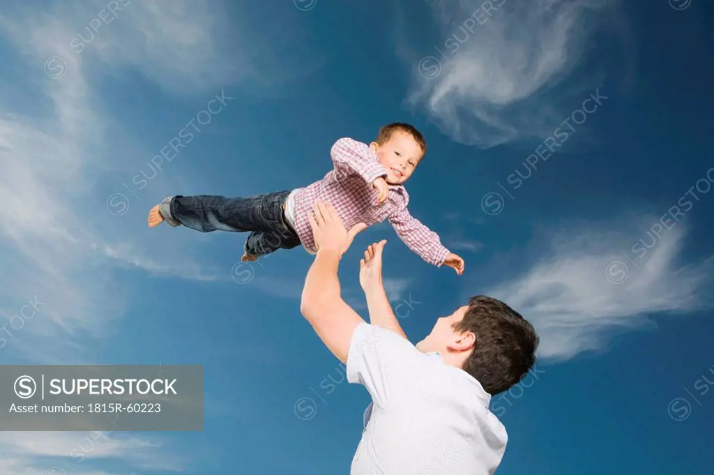 Germany, Schleswig Holstein, Amrum, Father lifting son 3_4 in the air, portrait