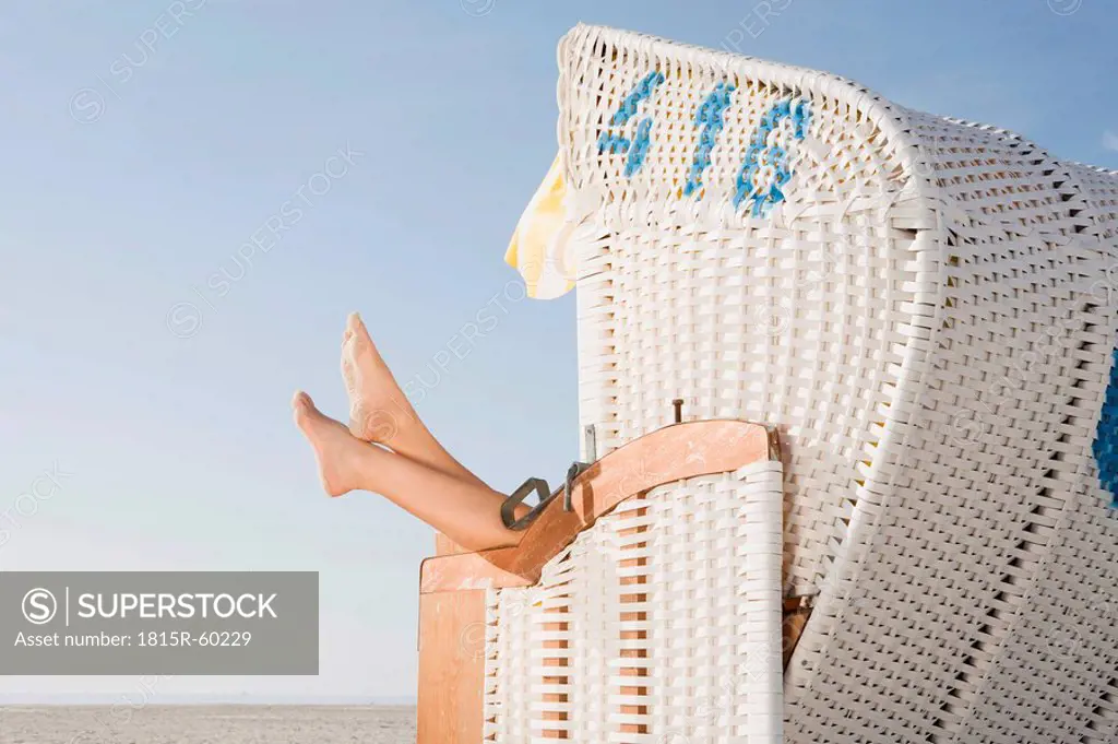 Germany, Schleswig Holstein, Amrum, Person relaxing in beach chair, low section