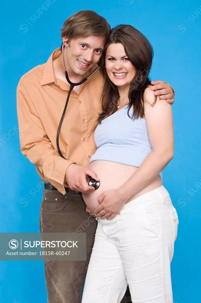 Man holding stethoscope on pregnant woman¥s belly