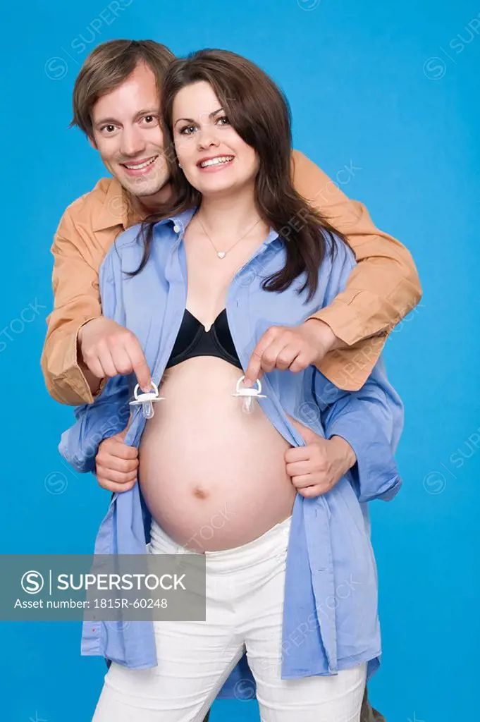 Pregnant woman, man holding soothers, smiling, portrait