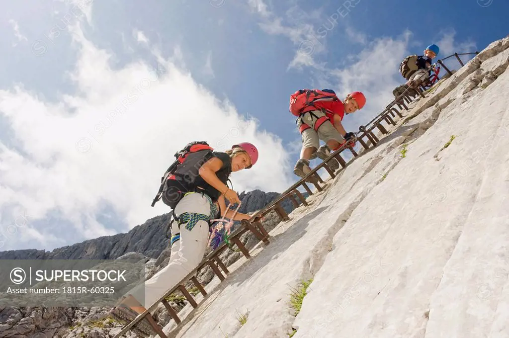 Germany, Garmisch_Partenkirchen, Alpspitz, Mother and sons 10_11, 12_13 climbing rock face on ladder
