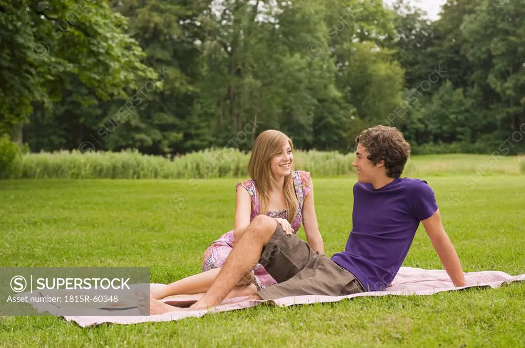 Germany, Bavaria, Starnberger See, Young couple sitting in meadow