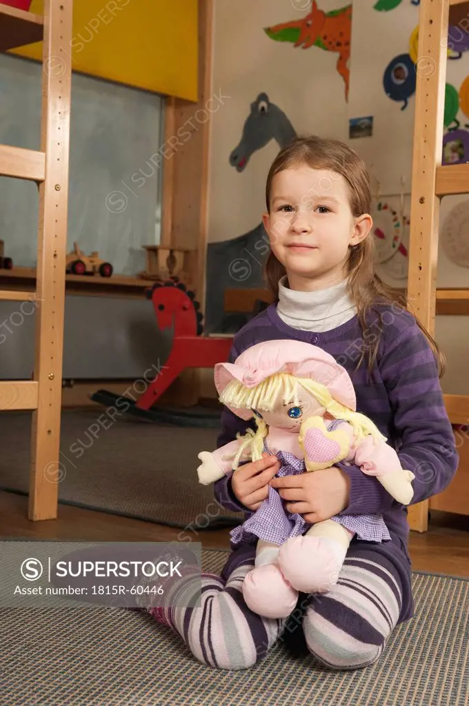 Germany, Portrait of a girl 4_5 in nursery holding doll