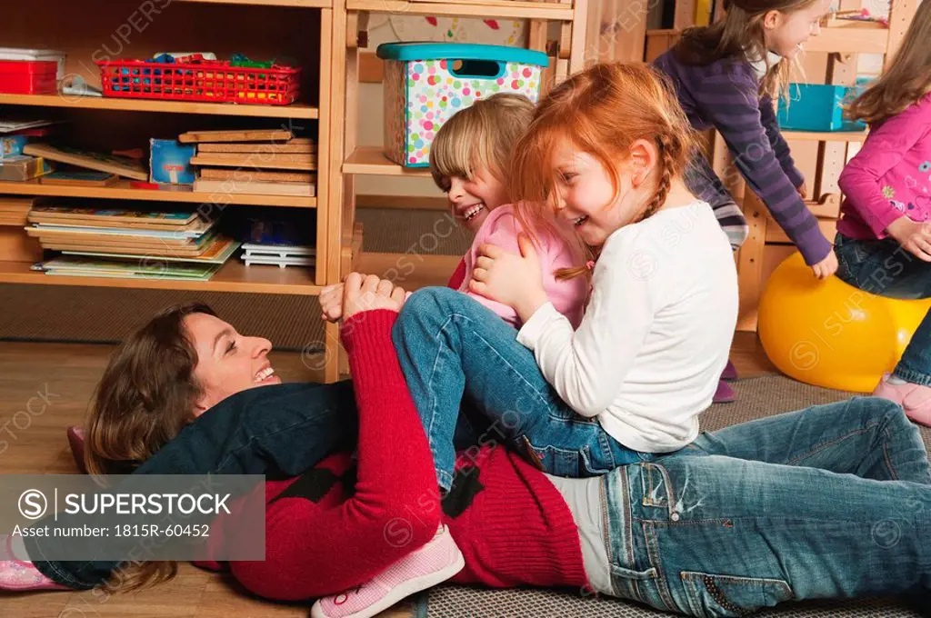 Germany, Nursery, Female nursery teacher and children playing together