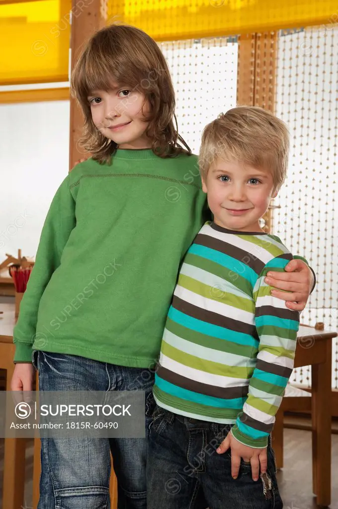 Germany, Two boys 3_4, 6_7 standing side by side, smiling, portrait