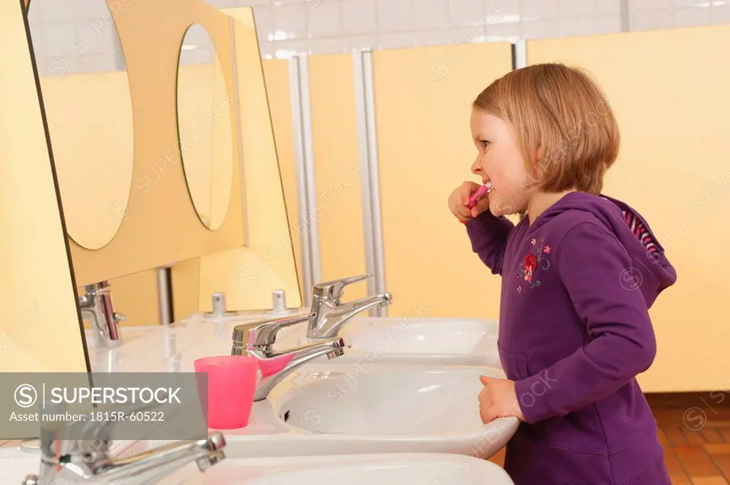 Germany, Gril 3_4 standing in front of mirror, brushing her teeth, side view, portrait