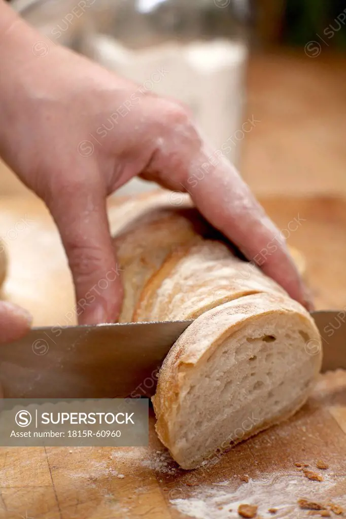 Person cutting baguette, close_up