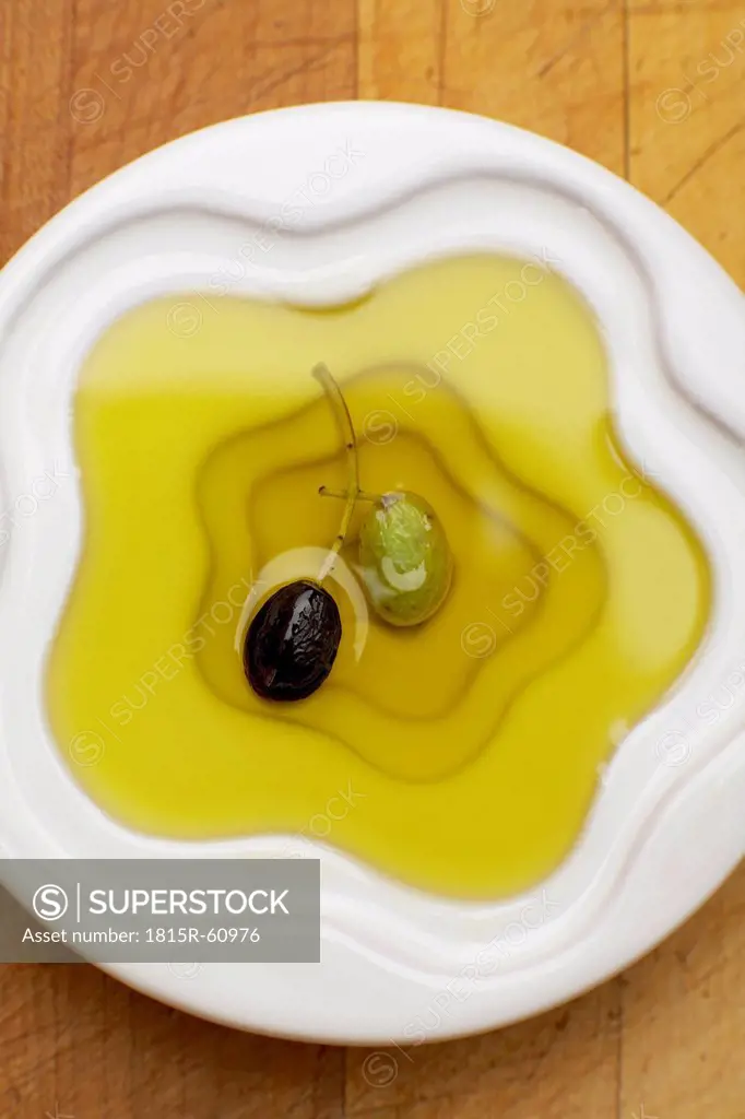Olive oil with olives in bowl, elevated view