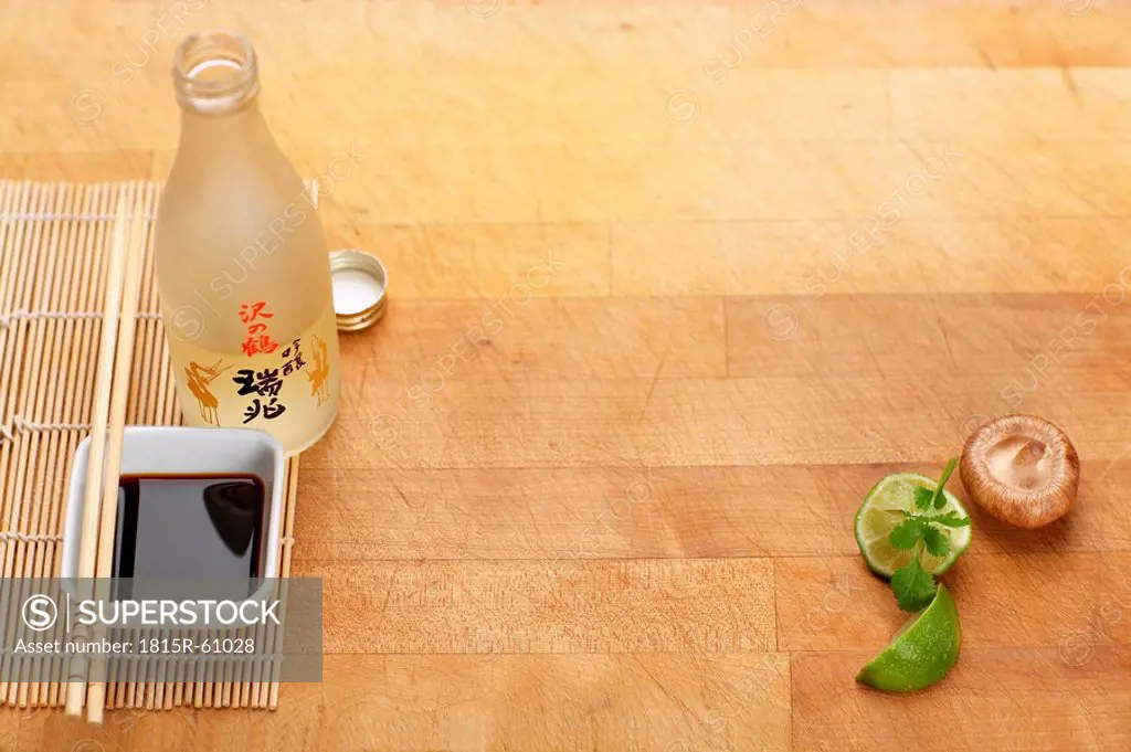 Bottle of sake wine, cilantro, soy sauce and chopsticks, elevated view