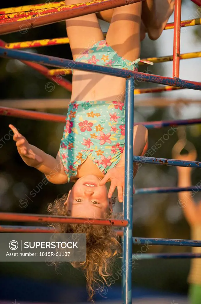 Germany, Baden Wí¼rttemberg, Girl 4_5 hanging upside down from junglegym, laughing, portrait