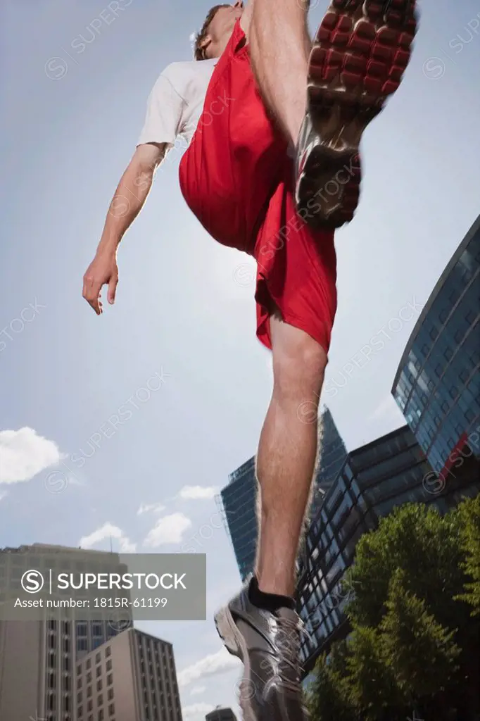 Germany, Berlin, Young man jumping in air, low angle view