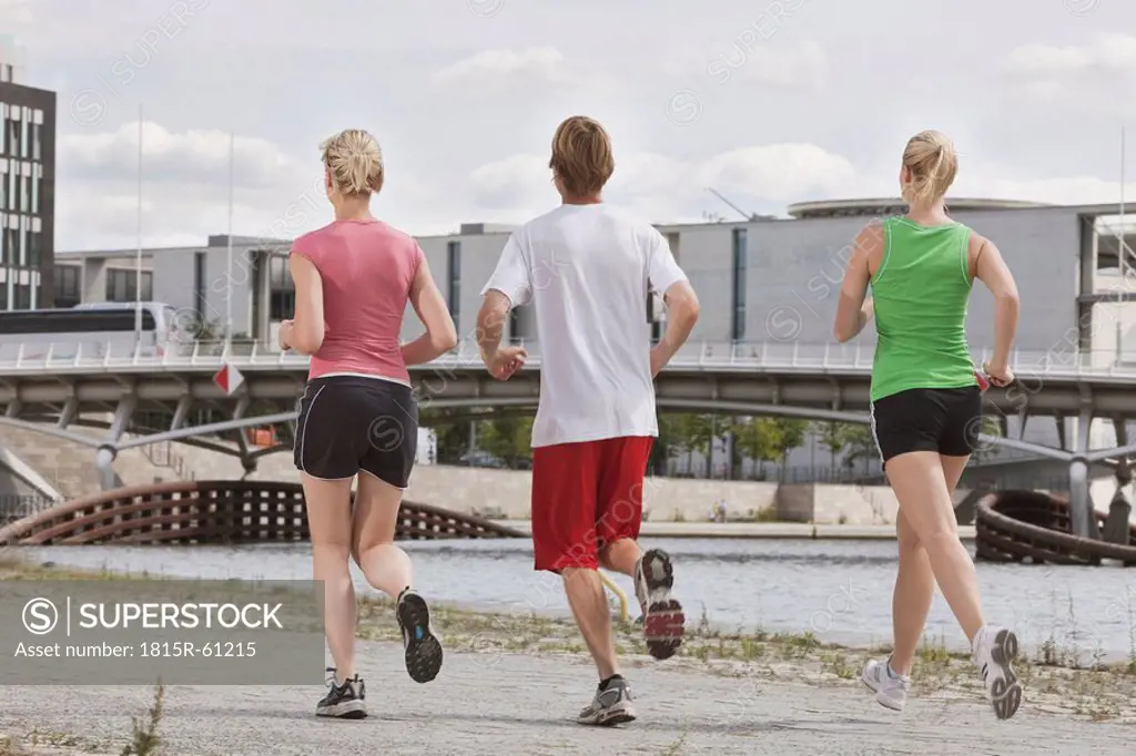 Germany, Berlin, Three person jogging in the city, rear view