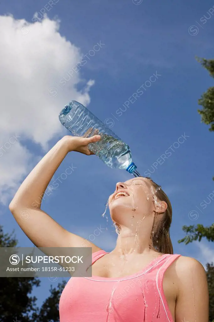 Germany, Berlin, Young woman pouring water over face, portrait