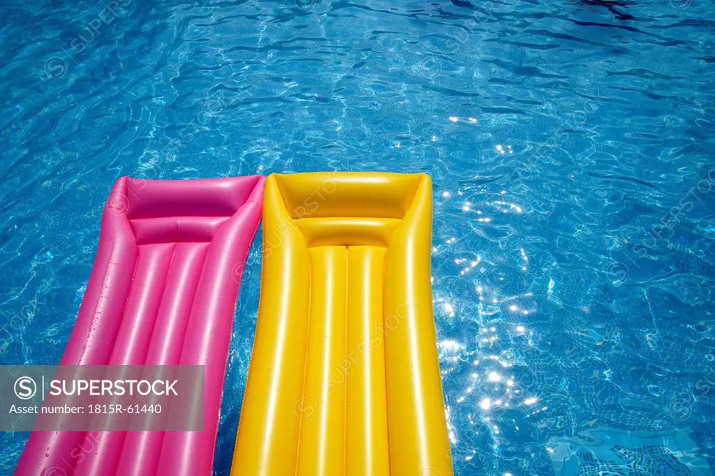 Two airbeds floating in pool, elevated view