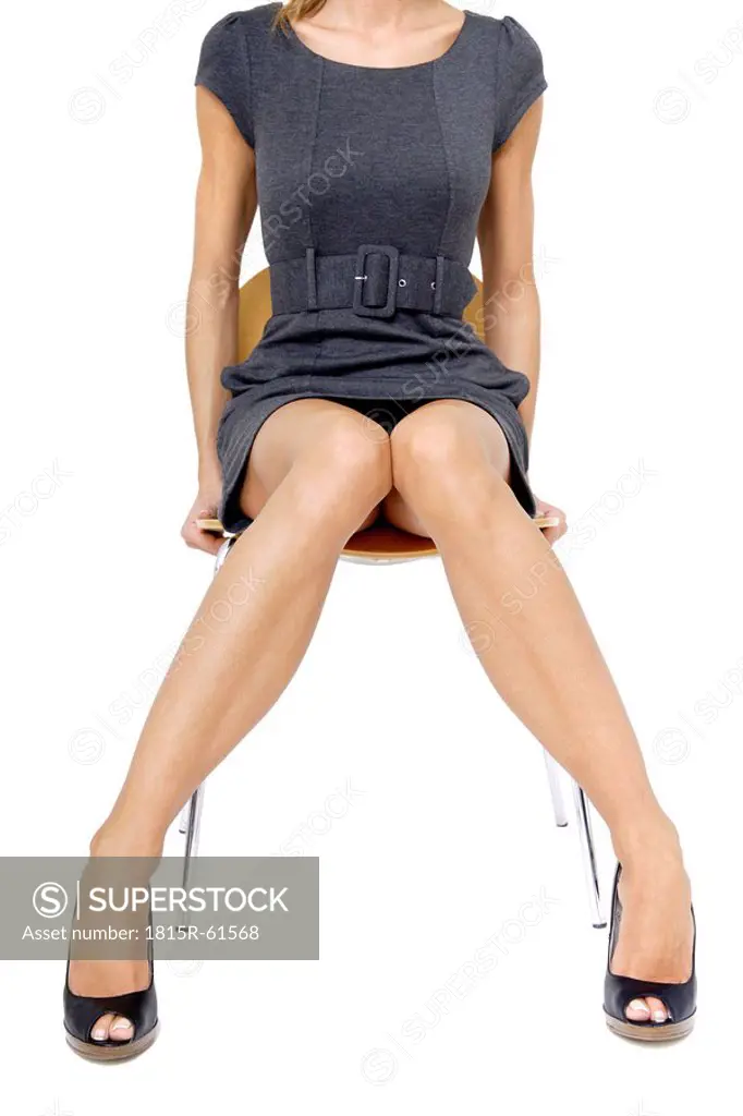 Young woman in mini dress sitting on chair, middle section