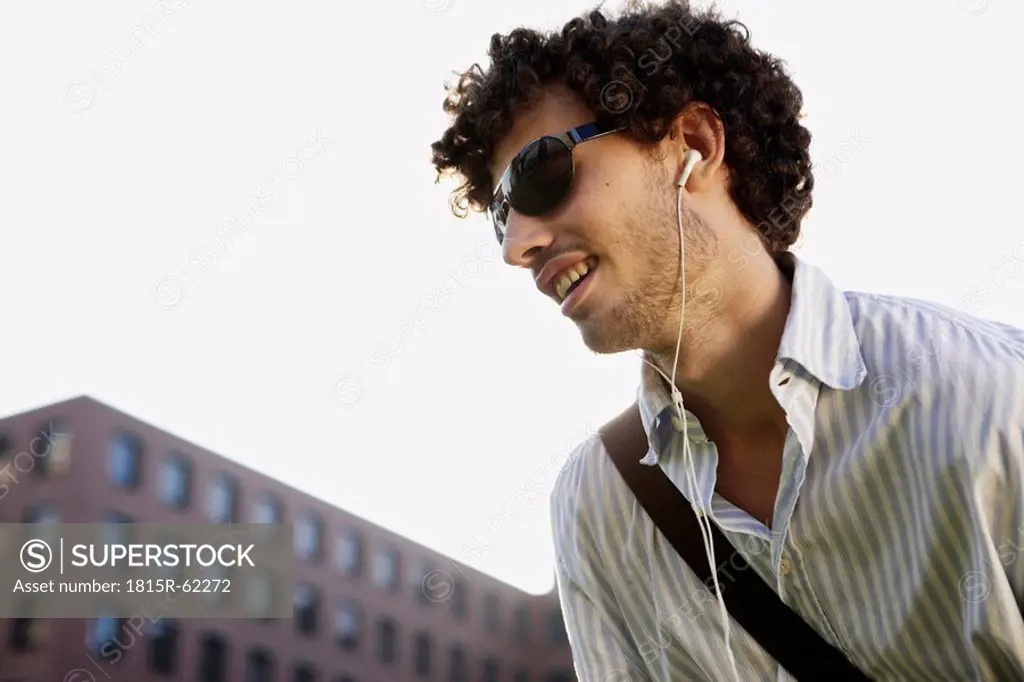 Germany, Berlin, Young man listening to MP3_Player
