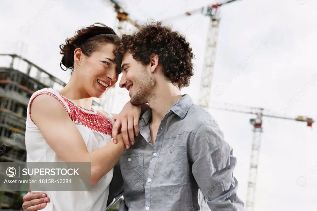 Germany, Berlin, Young couple in front of new building, cranes in background