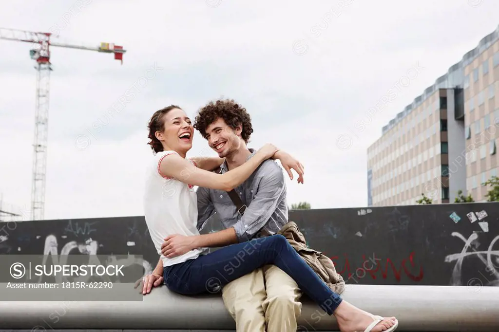 Germany, Berlin, Young couple in front of new building, cranes in background