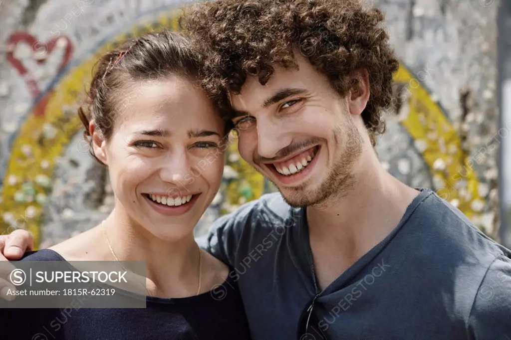 Germany, Berlin, Young couple standing in front of wall with graffiti, portrait, close_up