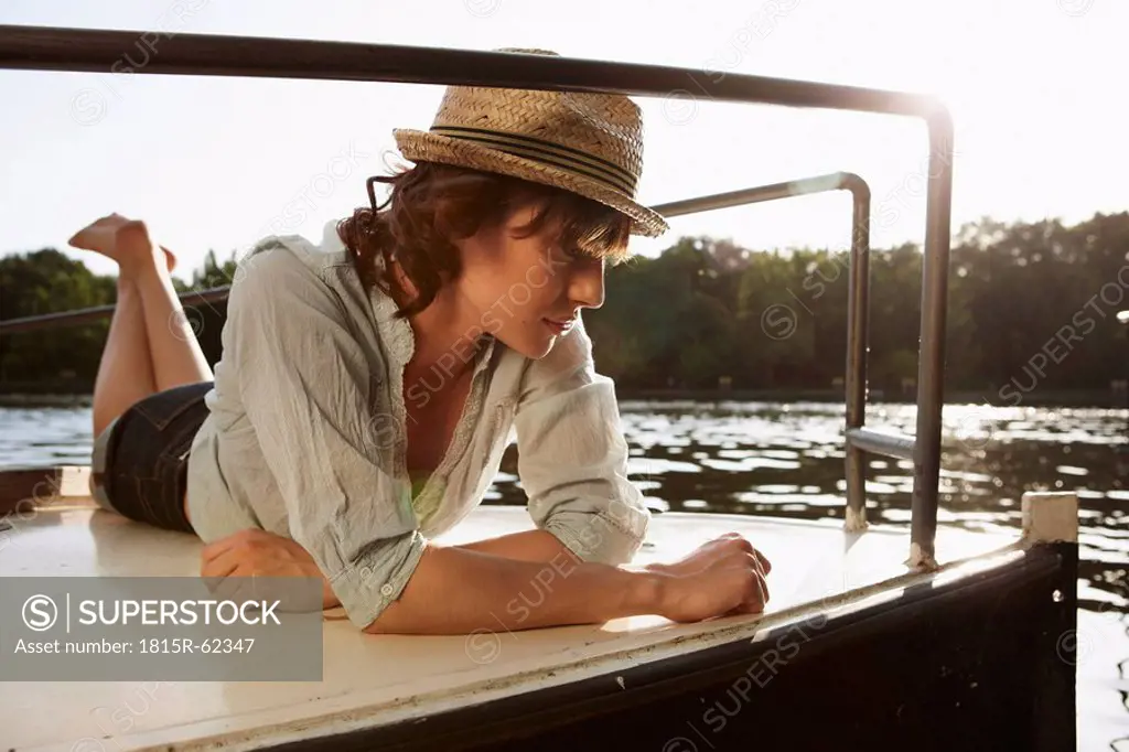 Germany, Berlin, Young woman lying on motor boat