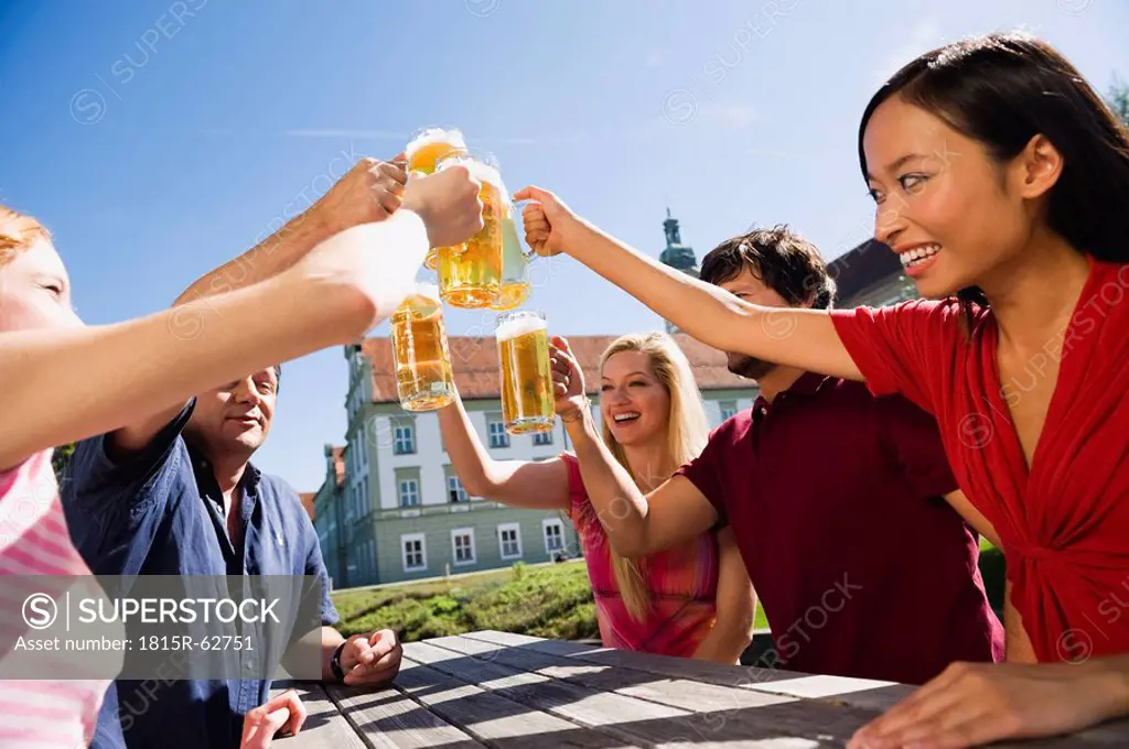 Germany, Bavaria, Upper Bavaria, Cheerful people toasting each other in beer garden