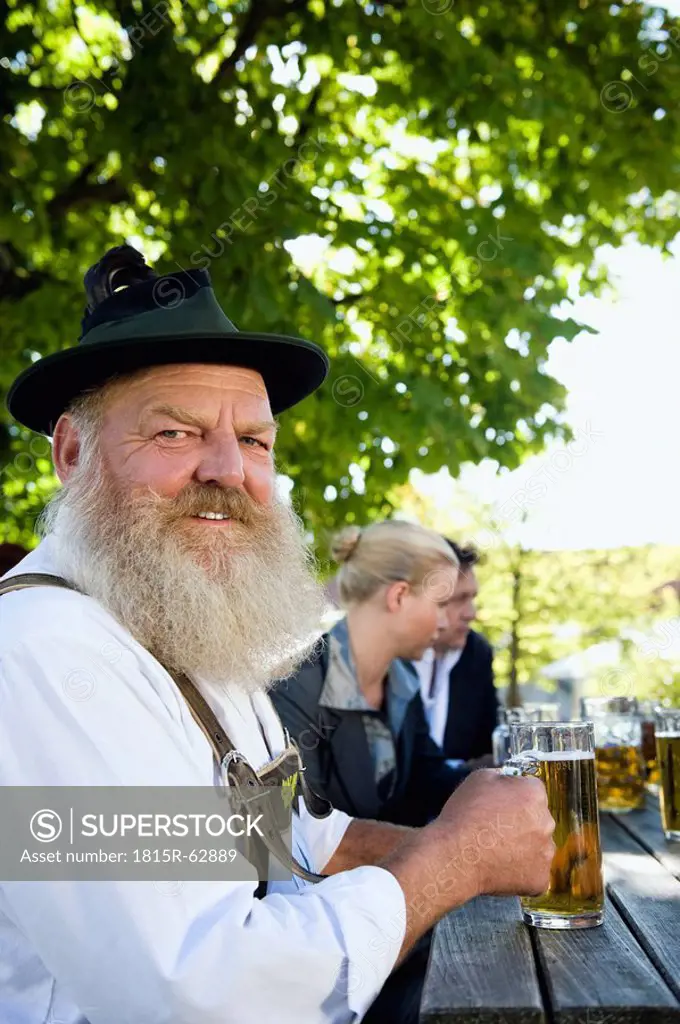 Germany, Bavaria, Upper Bavaria, Man in traditional costume holding beer stein, portrait