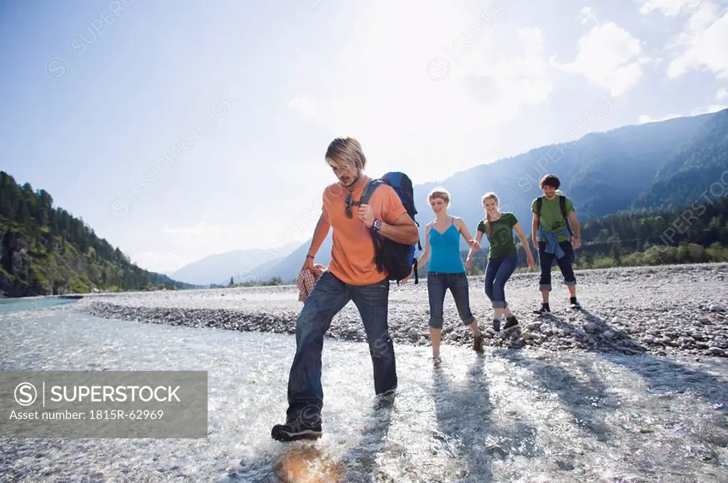 Germany, Bavaria, Tölzer Land, Young friends walking through river