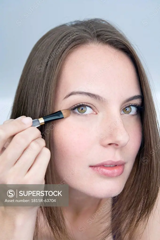 Young woman applying eye shadow, portrait, close_up