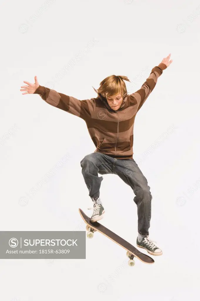 Teenage boy 13_14 performing jump on skateboard, arms out