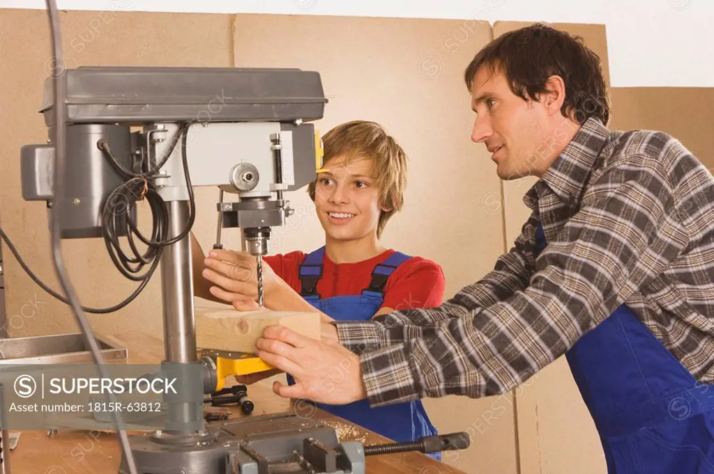Germany, father and son , Working on drill machine