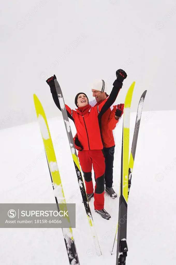 Italy, South Tyrol, Couple in winter clothes, rejoicing, skis in foreground