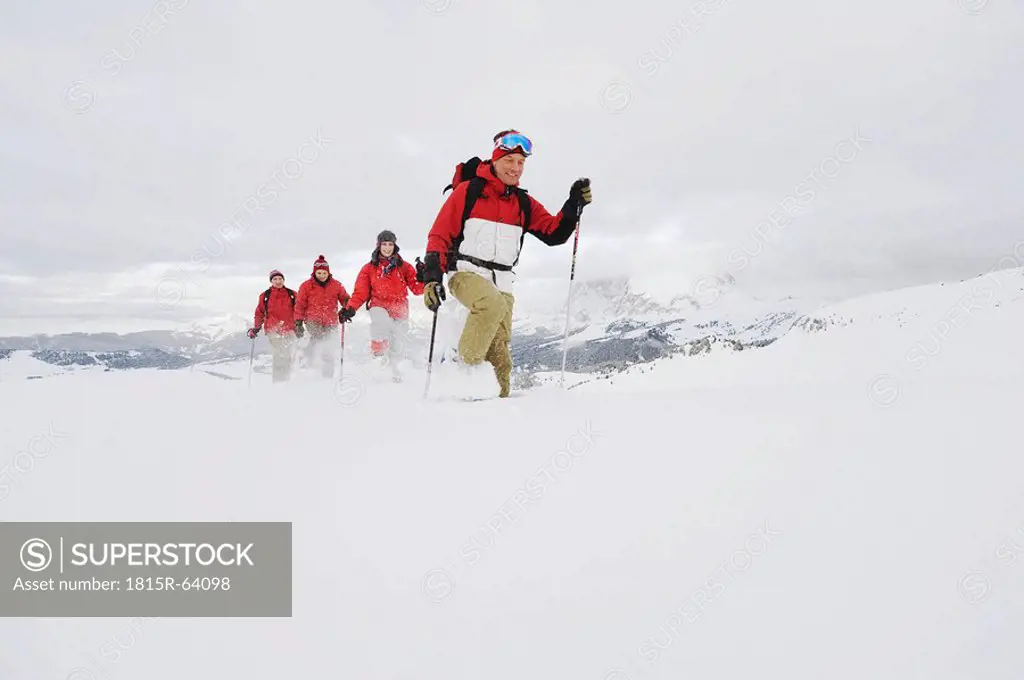 Italy, South Tyrol, Four people in a row, snowshoeing