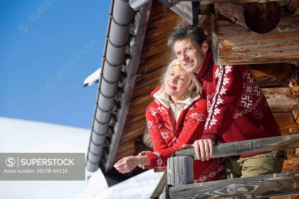 Italy, South Tyrol, Seiseralm, Couple standing on deck of log cabin