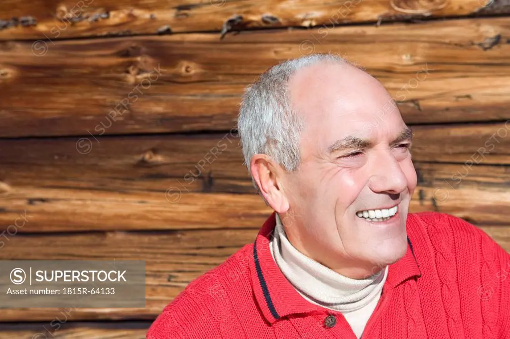 Italy, South Tyrol, Seiseralm, Portrait of senior man in front of wooden wall, close_up