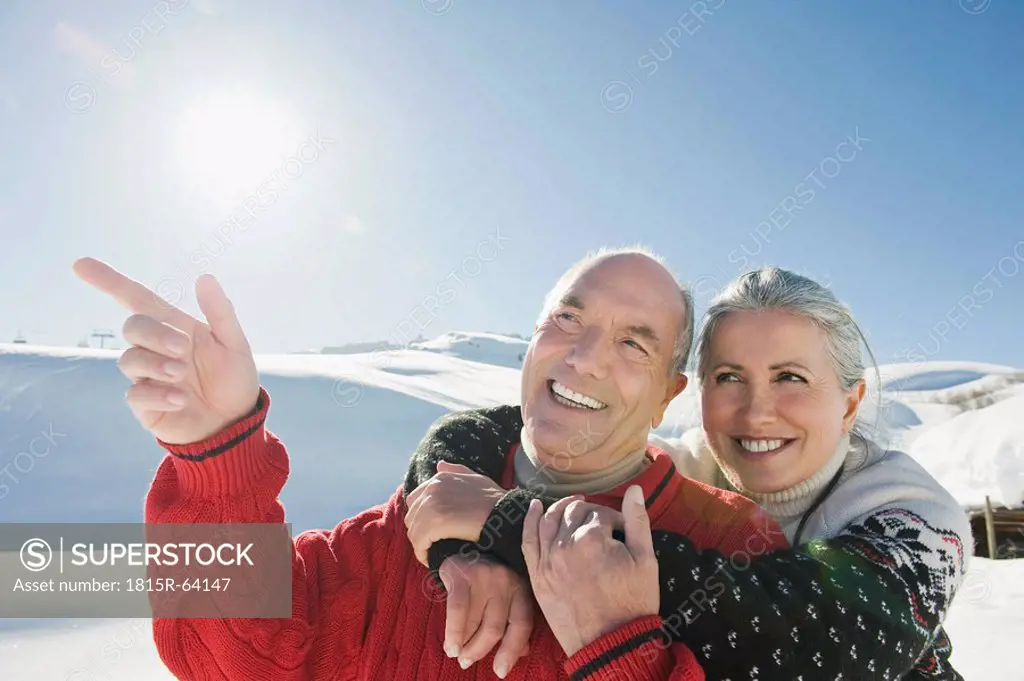 Italy, South Tyrol, Seiseralm, Senior couple in winter scenery, man pointing, portrait, close_up